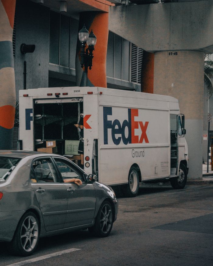 FedEx delivery truck unloading packages on a busy city street. Urban logistics and transportation concept.